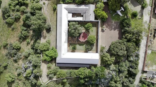 Drone flies west in bird's eye view of Queens Fort Military Museum and field of tanks, planes, and artillery on partially cloudy afternoon in Bloemfontein, South Africa