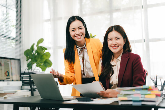 Two female colleagues are consulting and brainstorming. Two female accountants are preparing annual taxes together.