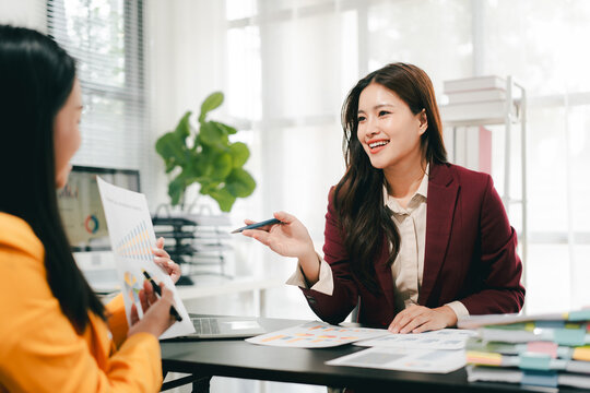Two female colleagues are consulting and brainstorming. Two female accountants are preparing annual taxes together.