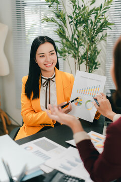 Two female colleagues are consulting and brainstorming. Two female accountants are preparing annual taxes together.