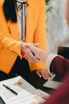 The businesswoman and men shook hands and signed the agreement. This demonstrates teamwork.