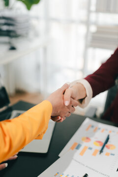 The businesswoman and men shook hands and signed the agreement. This demonstrates teamwork.