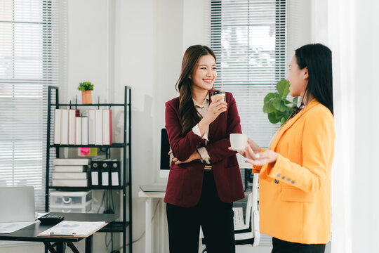 Two businesswomen were having an informal conversation. The two women greeted each other and began discussing a matter.