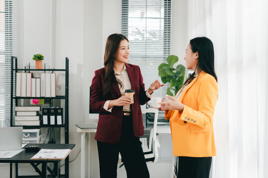 Two businesswomen were having an informal conversation. The two women greeted each other and began discussing a matter.