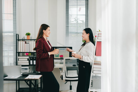 Two businesswomen were having an informal conversation. The two women greeted each other and began discussing a matter.