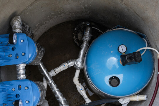 Modern water well system: hydropneumatic tank, filtration equipment, plumbing lines, pump, high-capacity water supply, domestic groundwater solution.