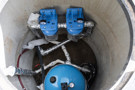 Water pump, filters, and pressure tank installed in well shaft, efficient artesian source, plumbing and treatment equipment for residential water supply.