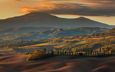 Fototapeta premium Tuscan countryside landscape with cypress trees and historic hill town, San Quirico d'Orcia, Italy.