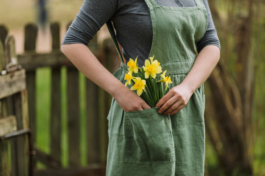 Woman holding spring flowers in a garden landscape