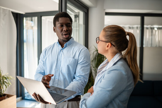 Business colleagues discussing project strategy with laptop in modern office setting