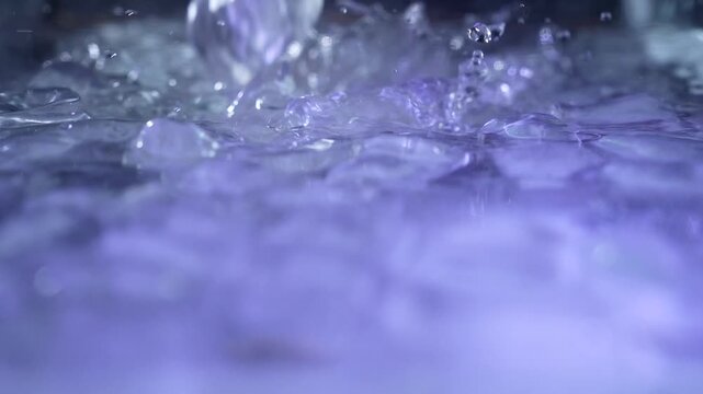 Top view of a ice cubes falling into water with oxygen bubbles, frost patterns, and soft light reflections. Concepts for beauty advertising, menu designs for bars and restaurants, cryotherapy.