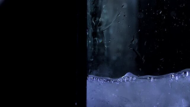 Ice cubes falling into a container of water against a black background. Concepts for beauty advertising, menu designs for bars and restaurants, cryotherapy.