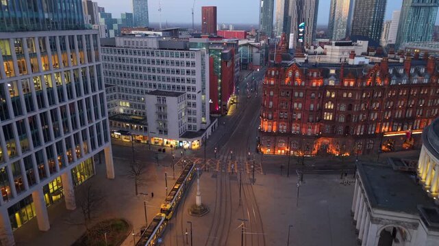 Aerial video over St Peter's Square in Manchester at dawn featuring a tram travelling towards Deansgate. 