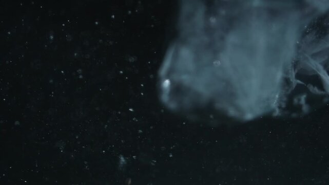 Ice cube falling into water with oxygen bubbles, frost patterns, and soft light reflections. Concepts for beauty advertising, menu designs for bars and restaurants, cryotherapy.
