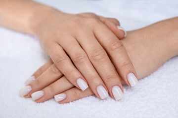 Fototapeta premium Woman showing her manicured hands with color nail polish on towel, closeup