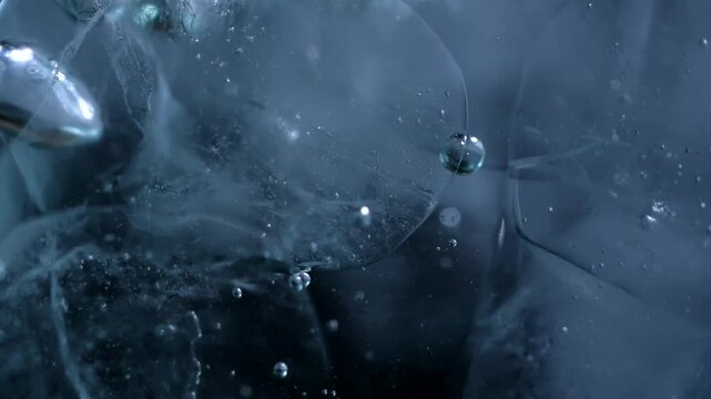 Close up of ice cubes underwater with oxygen bubbles, frost patterns, and soft light reflections. Concepts for beauty advertising, menu designs for bars and restaurants, cryotherapy.