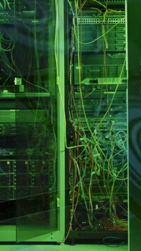 Vertical video: Camera drifting, LEDs blinking over open data center rack and cables for monitoring