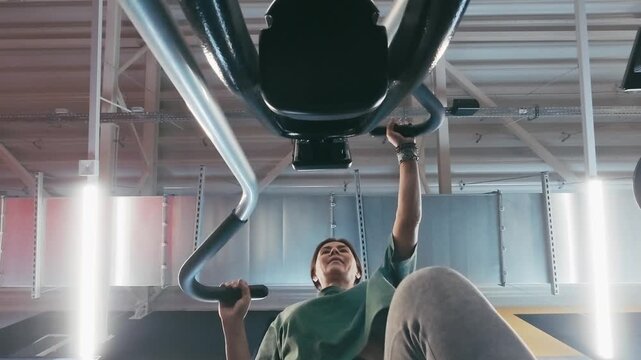 Woman Trains On An Elliptical Machine In The Gym, Viewed From Below