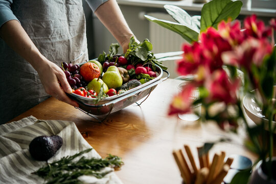 Hands serving a big tray with different fresh fruits and vegetables on the table. Harvest and healthy organic food concept.