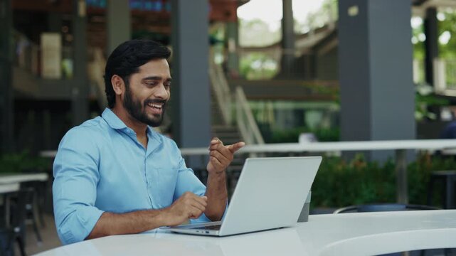 Portrait of happy Indian man using sign language on city street. Joyful bearded man smiling and saying Hi how are you I'm fine thanks. Communication and inclusion concept.