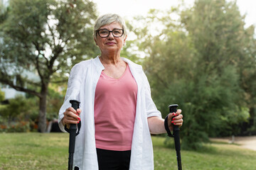 Active senior woman practicing nordic walking. Healthy sport for elderly people