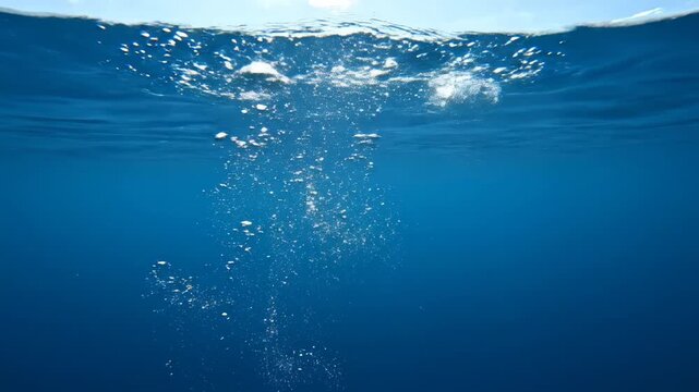 Submerged underwater view. Bubbles rising toward surface. Blue water
