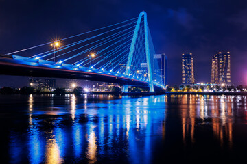 Obraz premium Night view of coastline with bridge and skyscrapers in Ho chi minh or Saigon city in Vietnam