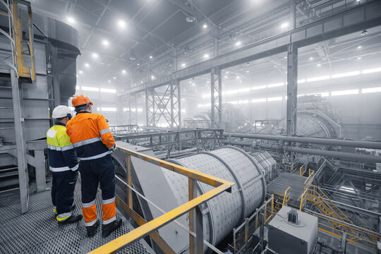 Industrial manufacturing mining workplace. Colleagues having discussion talk cooperation on during working process on background grinding ball mill with mineral gold ore