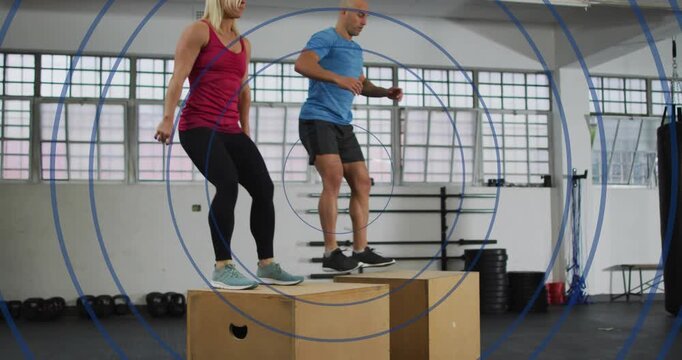 Workout partners initiating squat on wooden boxes, jumping down, rebounding for fitness training
