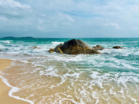 A sandy beach and turquoise water with rock formations as centerpiece at Chaweng Noi Beach, Koh Samui