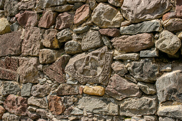 Fototapeta premium Ancient stone wall with carved ornaments and decorative elements, historic masonry texture and cultural heritage detail