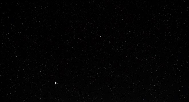 Dark starry sky with a scattering of tiny, bright, pinprick stars across the deep black canvas