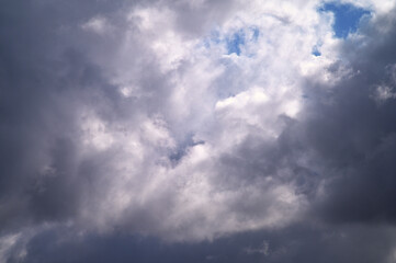Obraz premium Dramatic sky with dark storm clouds and patches of bright blue sky peeking through