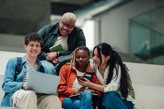 Diverse students collaborating on a project, using a laptop and smartphone for research and sharing ideas on campus