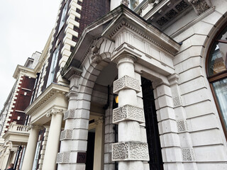 Fototapeta premium Grand classical building entrance with ornate columns and arch in London, UK city street