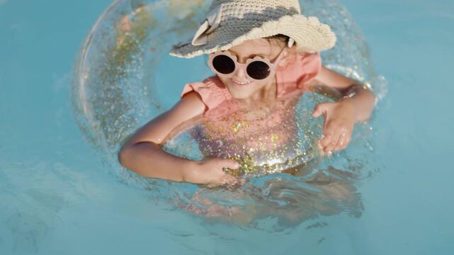 Cute funny toddler girl relaxing on inflatable toy ring floating in pool have fun during summer vacation. Child having fun in swimming pool. 