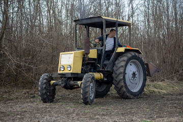 Obraz premium Farmer driving yellow agricultural tractor in rural field