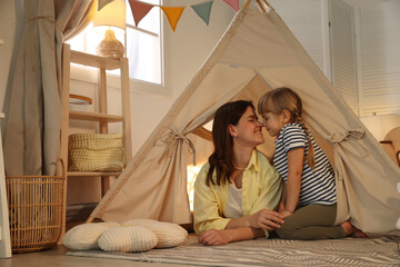 Mother and her daughter in toy wigwam at home © New Africa