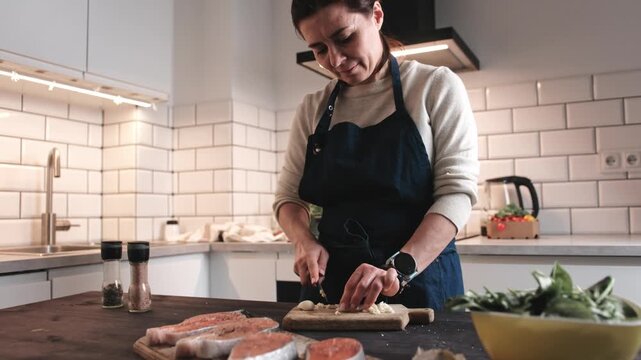 Woman Cutting Garlic Cooking Dinner In A Kitchen And Preparing Fish With Vegetables