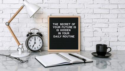 Obraz premium A well-organized modern desk setup featuring a motivational letter board, an alarm clock, and an open notebook, inspiring focus and productivity for daily routines.