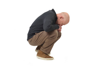Side view of a thoughtful squatting man looking down © Curto