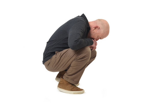 Side view of a thoughtful squatting man looking down