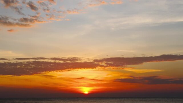 Dramatic ocean sunset with vibrant colors and cloudy sky over calm sea