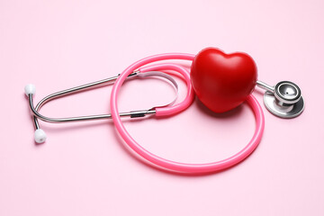 Fototapeta premium Stethoscope and heart figure on pink background