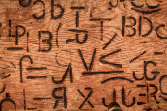 Cattle branding symbols burned into wood, western ranch heritage and livestock marks