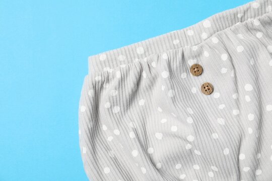 Baby bloomers on light blue background, top view. Space for text