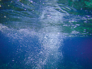 Fototapeta premium Bubbles under the sea in the crystal clear green sea water. Mediterranean bubbles. Real image very suitable for backgrounds, Rising Bubbles in Deep Underwater, Under with bubble. Great for background.