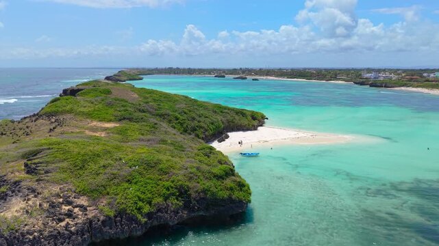 Aerial view of the turquoise coastline and rocky cliffs featuring a small white sand beach and a blue boat anchored in Watamu, Kenya.
