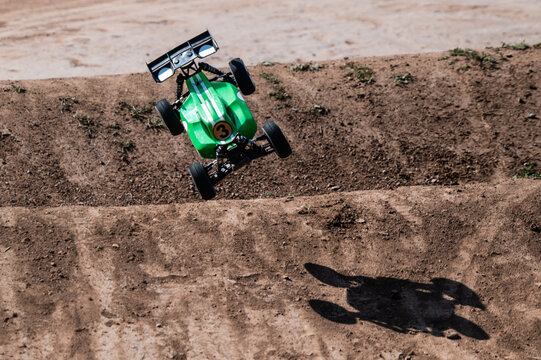 Green radio-controlled car jumping on dirt track