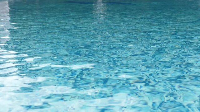 Clean swimming pool with clear blue water and sun reflections